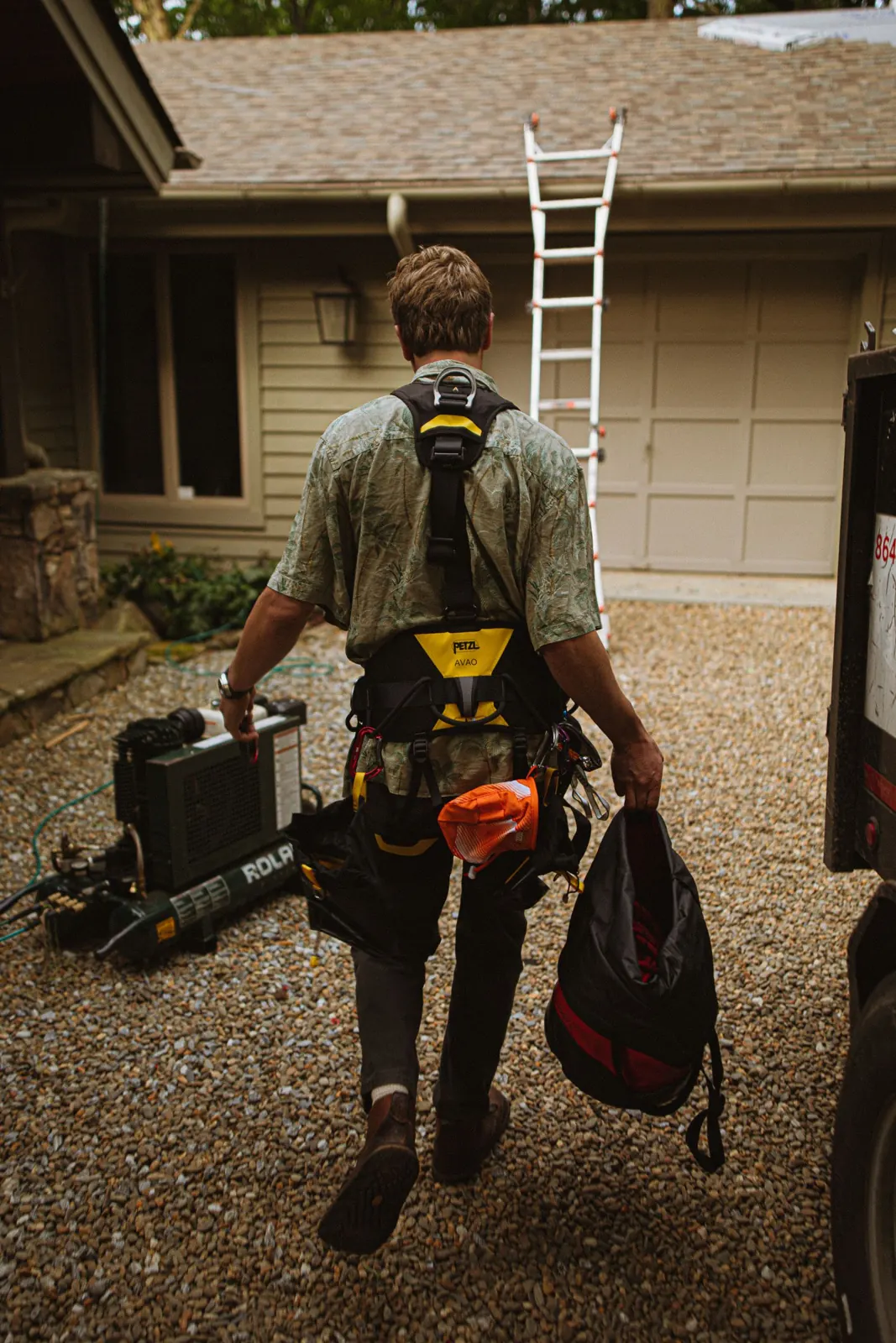 Roofer with safety harness arriving to repair a roof